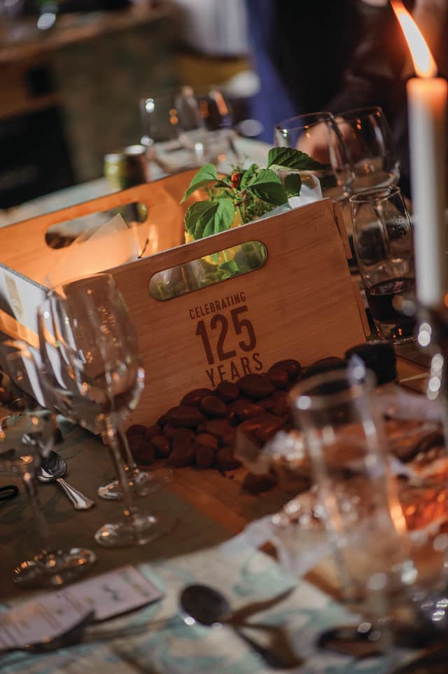 A wooden fruit crate marked Celebrating 125 Years among glasses and candlelight on the gala dinner table