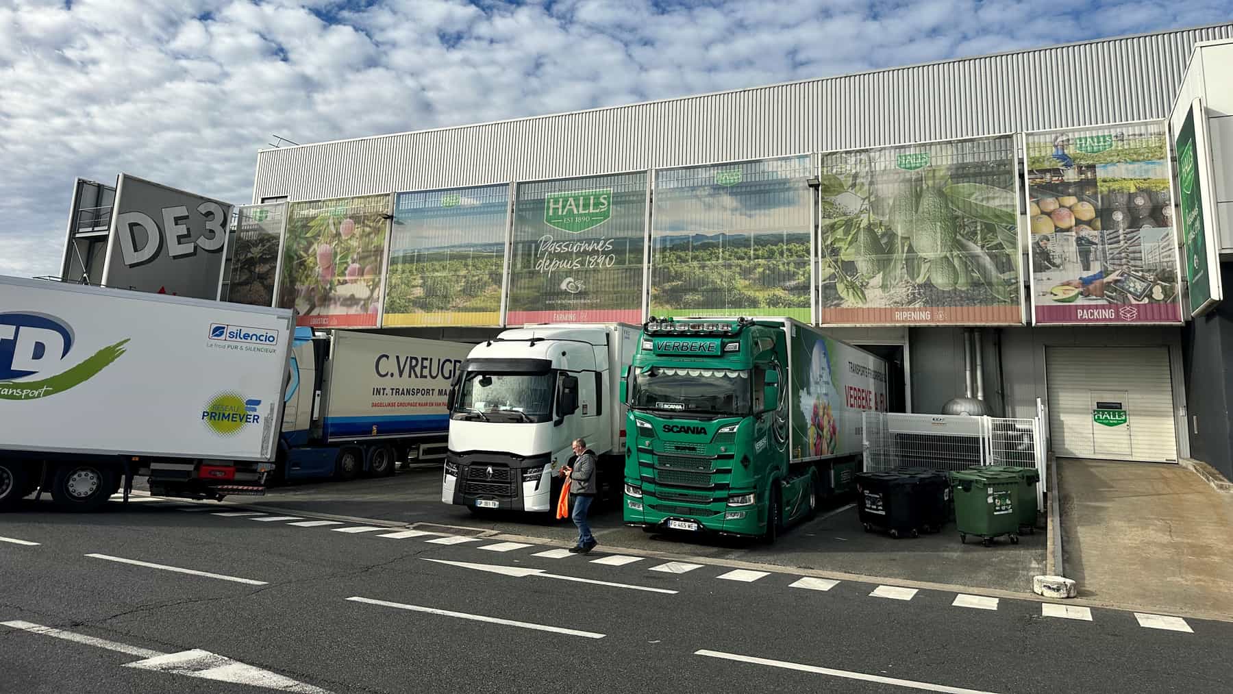 Trucks wait at the loading bays of the Halls facility in France, beneath banners reading ‘Passionnés depuis 1890’