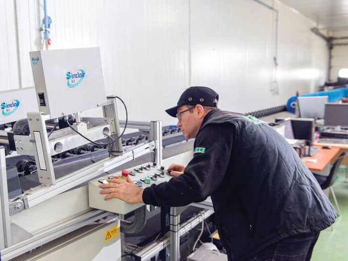 A technician operates the control panel of a Sinclair iQ grading machine in the packhouse